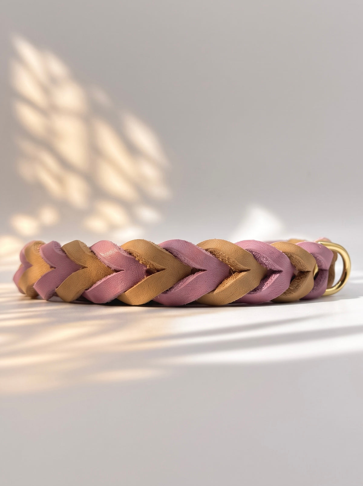 Ein geflochtenes Lederhalsband in Rosa, Flieder und Braun. Es ist handgefertigt, individuell anpassbar und konfigurierbar. Die Details der Flechtung sind sichtbar. 