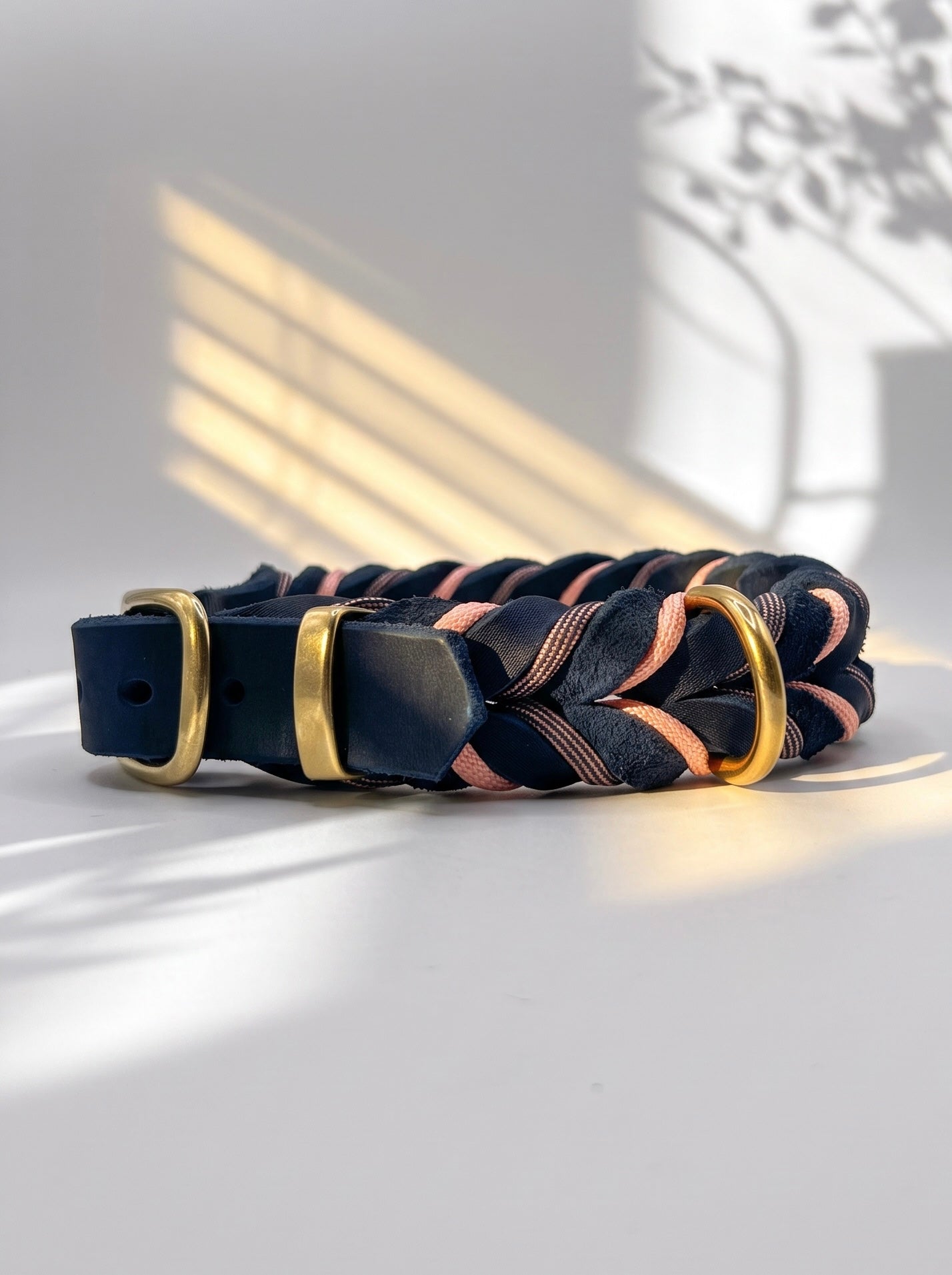 Lederhalsband geflochten aus Fettleder in der Farbe Dunkelblau mit rosé farbenen Details und goldenen Beschlägen. Individuell anpassbar in breite. Ansicht Seite schnalle