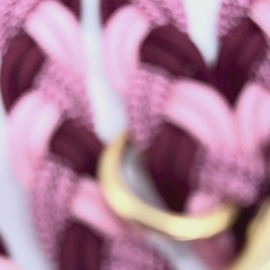 Paracordleine in rosa, rot und burgundy geflochten mit Messing Beschlägen. Aufnahmen von den Details der Leine 